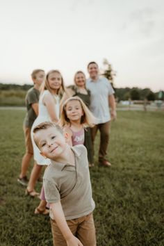 a group of people standing on top of a grass covered field next to each other