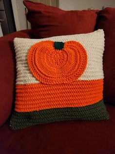 a crocheted pumpkin pillow sitting on top of a couch