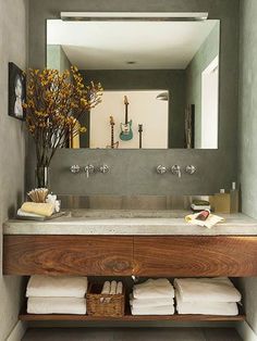 a bathroom sink sitting under a mirror next to a wooden shelf with towels on it