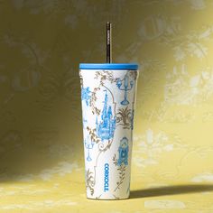 a blue and white cup with a straw sticking out of it's lid sitting on a yellow surface