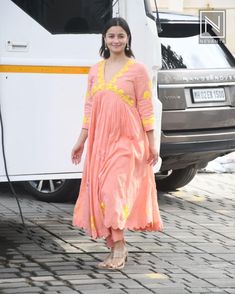 a woman standing in front of a bus on a brick road next to a white van