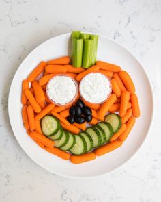 a plate with carrots, cucumbers and celery in the shape of a face