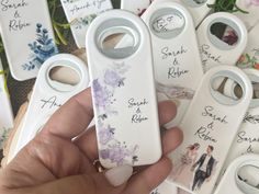 a person holding several wedding favors in front of some flowers and other personalized items