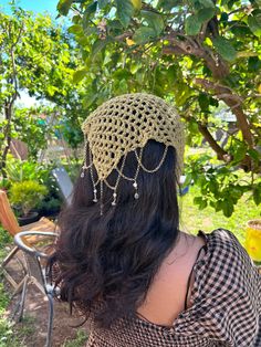 the back of a woman's head wearing a crocheted hat with pearls