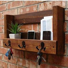 a wooden shelf with key hooks and keys hanging from it's sides next to a brick wall