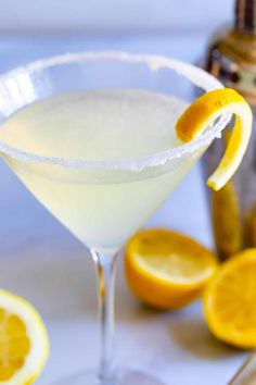 a glass filled with white liquid and garnished with lemon wedges next to an orange slice