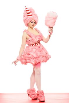 a woman in a pink dress and hat holding two lollipops