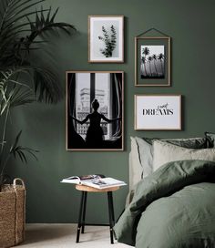 a bedroom with green walls and pictures hanging on the wall above it, along with a small side table