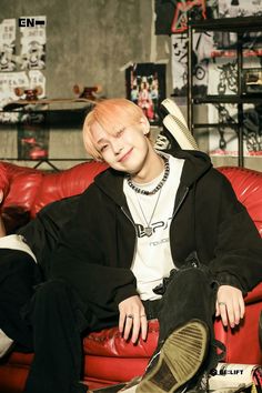 a young man sitting on top of a red couch