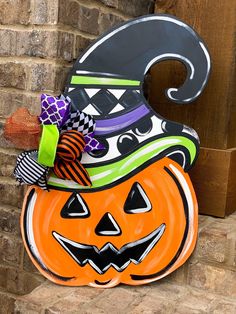 a halloween pumpkin with a witch hat on it's head sitting in front of a brick wall