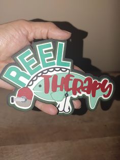 a hand holding a sticker with the word reel therapy in red, white and green