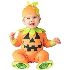 a baby in a pumpkin costume sitting on the ground with his hands up and smiling