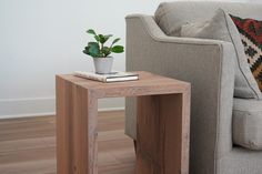 a small wooden table with a potted plant sitting on it next to a couch