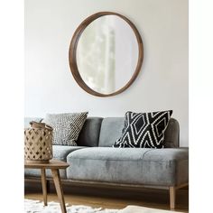 a living room with a gray couch and round mirror on the wall