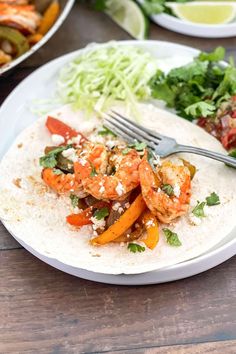 a white plate topped with shrimp and veggies on top of a wooden table