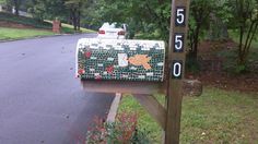 a mailbox sitting on the side of a road next to a tree and bushes