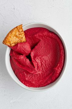 a white bowl filled with red food next to a piece of pie on top of it