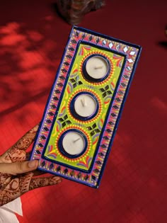 a person holding up a decorated box with candles in it