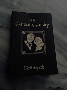 the great gatsby by f scott frigerold is on top of a marble table