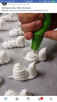 someone is decorating small white sculptures on a table