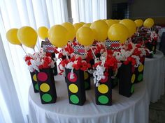 a table topped with black bags filled with yellow and red balloons next to white tables