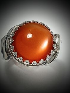 ORANGE MOONSTONE, Ring, Very Rare Quality! 11.5mm, AAA. Gem, Sterling Silver, Size 61/2, RC3.orang.ms.Please tell me your size. RING BOX#4 This is the only orange moonstone I have in my collection. The stone is rare and beautiful.  VERY RARE QUALITY GREAT CHATOYANCY! GREAT POLISH! GREAT CUT GREAT COLOR All of my stones are hammer set. We design jewelry to last a lifetime. This ring is excellent and strong. It should last forever.  Thank you for considering my work. LuvBruce Location: Celtic Jewelry Elegant Silver Ring Cabochons, Elegant Round Orange Gemstones, Round White Gold Polished Cabochons, Polished White Gold Cabochons, Polished Opal Ring For Anniversary, Polished Finish Opal Ring For Anniversary, Formal Polished Round Moonstone Ring, Formal Polished Moonstone Ring, White Gold Round Cabochon Gemstones