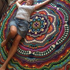 a woman laying on top of a multicolored rug with her arms stretched out