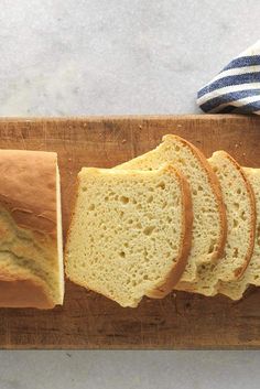 sliced loaf of bread sitting on top of a cutting board next to a blue and white towel