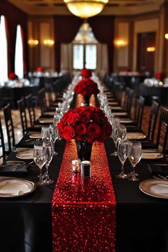 the long table is set with black and red linens, silverware, and rose centerpieces