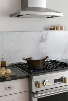 a stove top oven sitting inside of a kitchen next to a pot on the burner