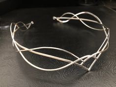 I have fabricated a sterling silver Celtic and Elvish inspired bridal tiara which is designed to be worn for a wedding, a Renaissance event, or hand-fasting ceremony. An artisan circlet with a Middle Earth feel! This piece can be unisex and comes without a gemstone. This piece will fit 3/4's around the head and is tied off, in the back, by an elastic jeweler's cord so that it will remain snug and in place while in motion. This works better than using a chain link, which can leave a circlet too t Elegant Adjustable Silver Headpieces, Elegant Silver Headpiece With Structured Crown, Elegant Silver Headpiece With Teardrop Crown, Elegant Silver Teardrop Crown Headpiece, Silver Teardrop Crown Headpiece, Silver Crown Headpiece For Wedding, Elegant Silver Crown Headband, Elegant Silver Headband For Wedding, Adjustable Crown Design Headpiece For Weddings