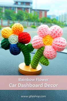 a crocheted flower sitting on top of a car dashboard with the words rainbow flower car dashboard decoration