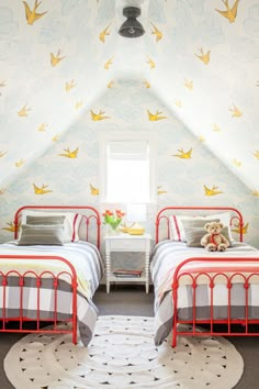 two beds in a bedroom with birds painted on the walls