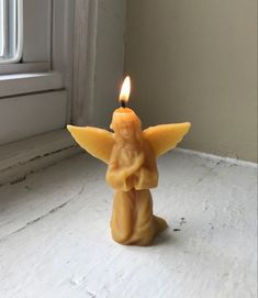 a candle with an angel on it sitting in front of a window