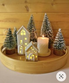 a candle is lit in front of some small houses on a tray with pine trees