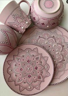 three pink plates and two cups with beaded designs on them