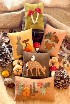 a pile of pillows sitting on top of a wooden floor next to pine cones and other decorations