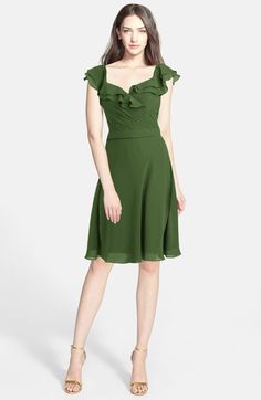 a woman is wearing a green dress with ruffles on the shoulders and shoulder