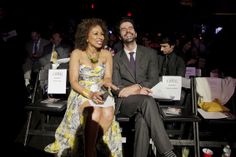 a man and woman sitting next to each other in front of a crowd at an event