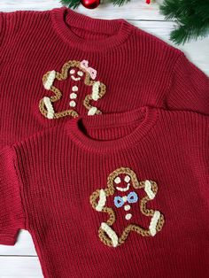 two red sweaters with ginger cookies on them sitting next to a christmas tree and decorations