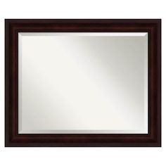 a brown framed mirror sitting on top of a white wall