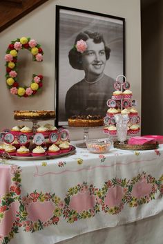 a table topped with cakes and cupcakes on top of a table covered in flowers