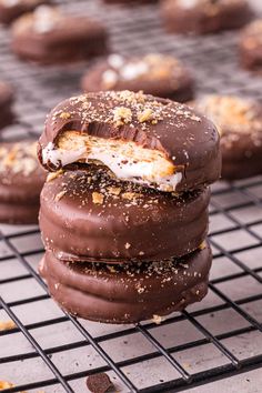 chocolate covered cookies with white frosting and sprinkles on a cooling rack