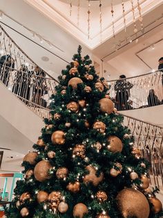 a christmas tree with gold and silver ornaments on it in the middle of a lobby