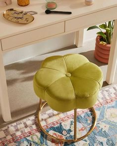 a green stool sitting in front of a white table with a mirror and other items on it