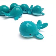 several small blue plastic toy dolphins on a white surface with one laying down and the other standing up