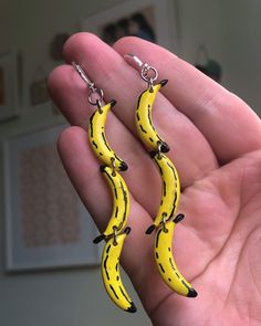 a pair of banana shaped earrings hanging from a persons hand