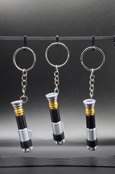 four different types of lighters hanging from a line on a black surface with two keychains attached to them