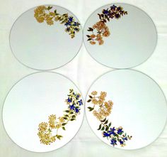 four white plates with gold and blue flowers on them