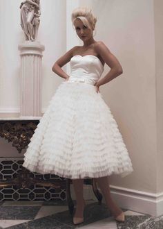 a woman in a white dress standing next to a statue